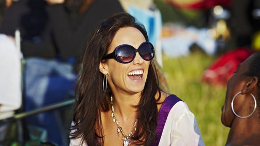 Two audience members laugh in conversation at an outdoor performance.